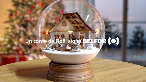 Boule à neige sur une table en bois avec texte : Un conte de Noël signé avec BELFOR