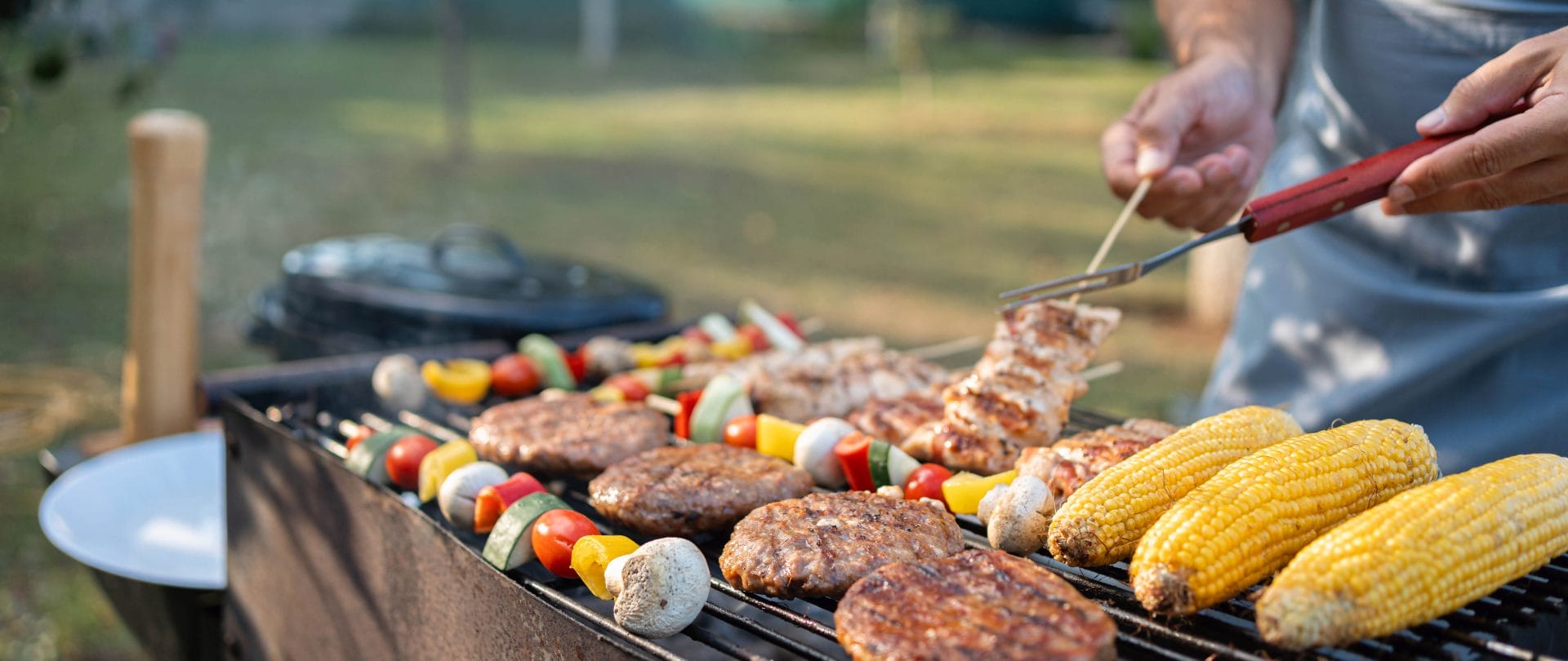 Grill mit Fleisch, Gemüsespießen und Maiskolben belegt