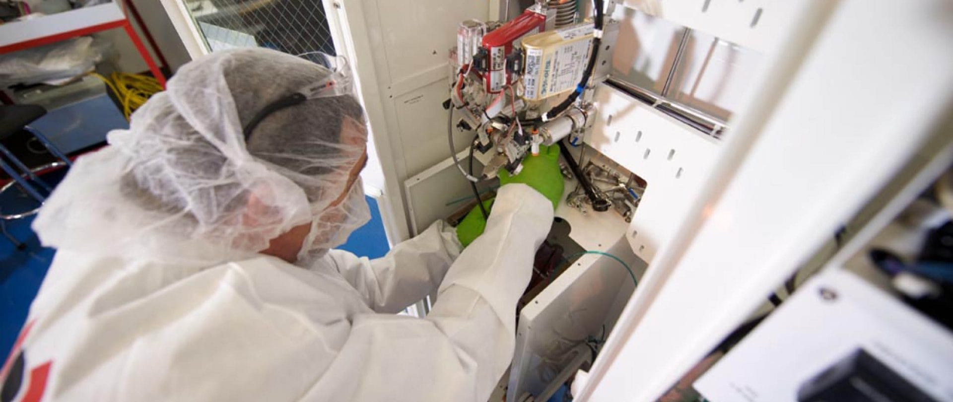 BELFOR-Mitarbeiter im weißen Schutzanzug bei der Reinigung elektronischer Teile