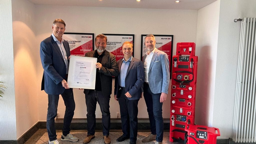 Überreichung ISO 27001‑Zertifikat von Ralph Freude, Leiter der Business Line ICT bei TÜV Rheinland, an Elvir Kolak (CEO), Dr. Mark Nusselein (CFO) und Mirko Blüming (CISO) von BELFOR Europe