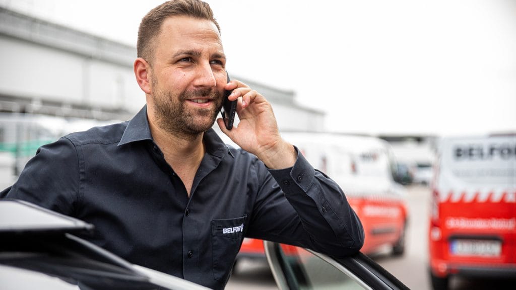 Un chef de projet de BELFOR souriant tout en parlant à quelqu'un au téléphone