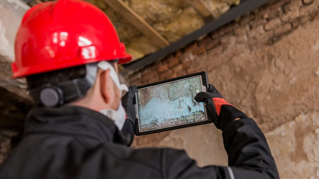 Un employé utilise une tablette pour évaluer les dommages d'une structure.