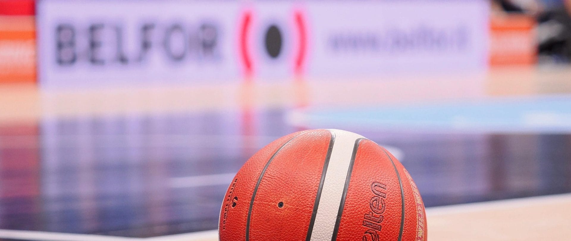 Una palla in un campo da basket con sullo sfondo il logo BELFOR