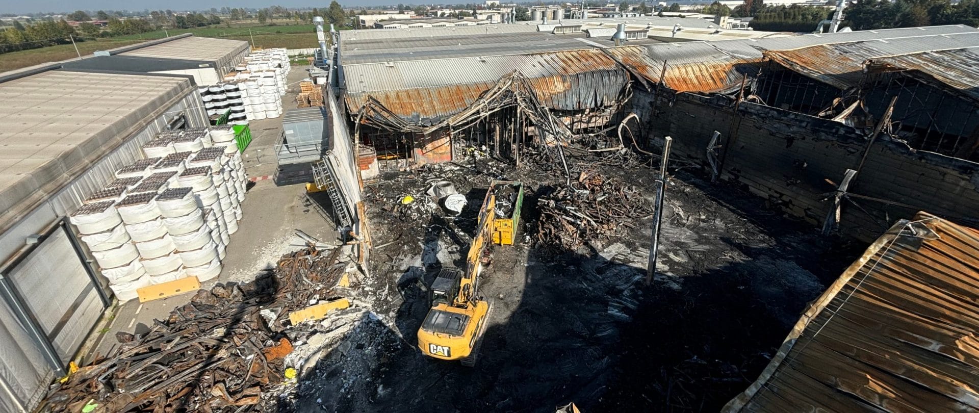 Escavatore che sta demolendo un fabbricato danneggiato da un incendio