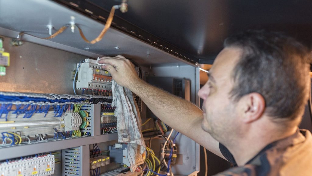 BELFOR technicus reinigt elektronica met een doek