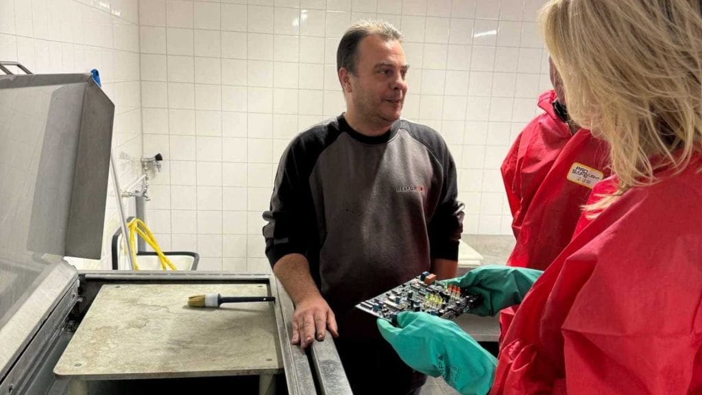 Personen in werkkleding bekijken een gereinigde printplaat.