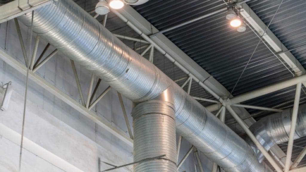 Industrial ducts running along the ceiling of a building, showcasing a complex ventilation system.