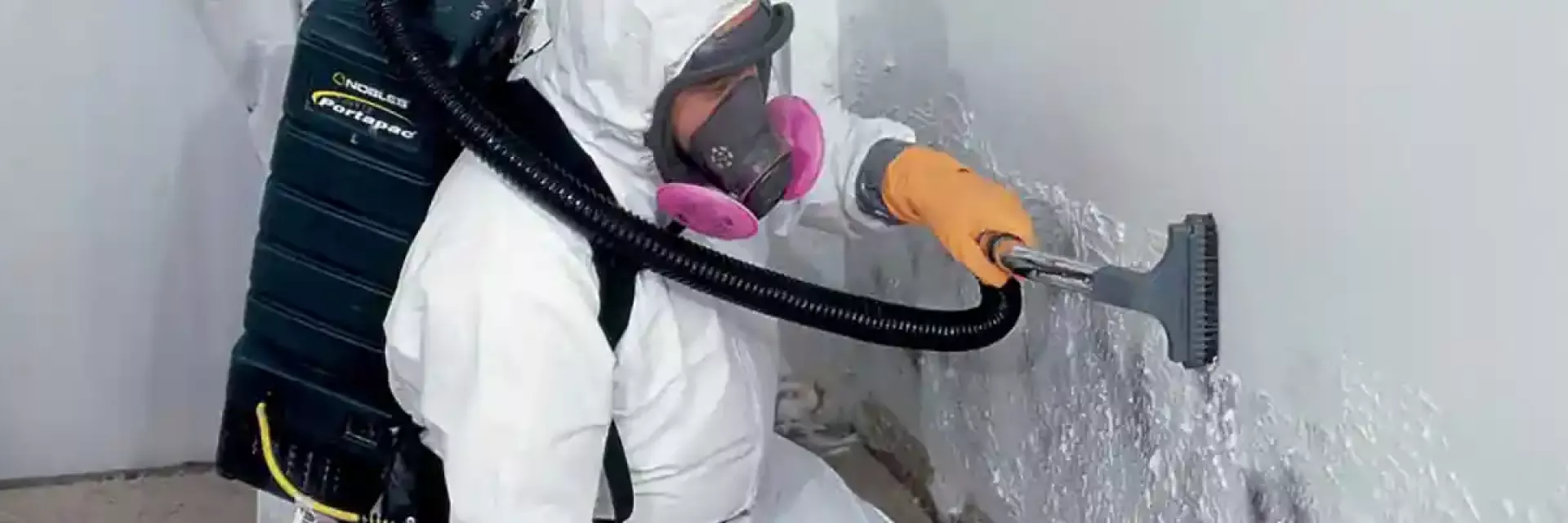 BELFOR technician vacuums mold from wall