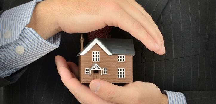 Hands protecting house as symbol of insurance