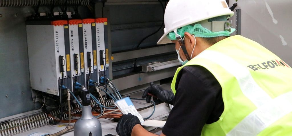 A BELFOR employee with helmet and gloves working on a swithboard