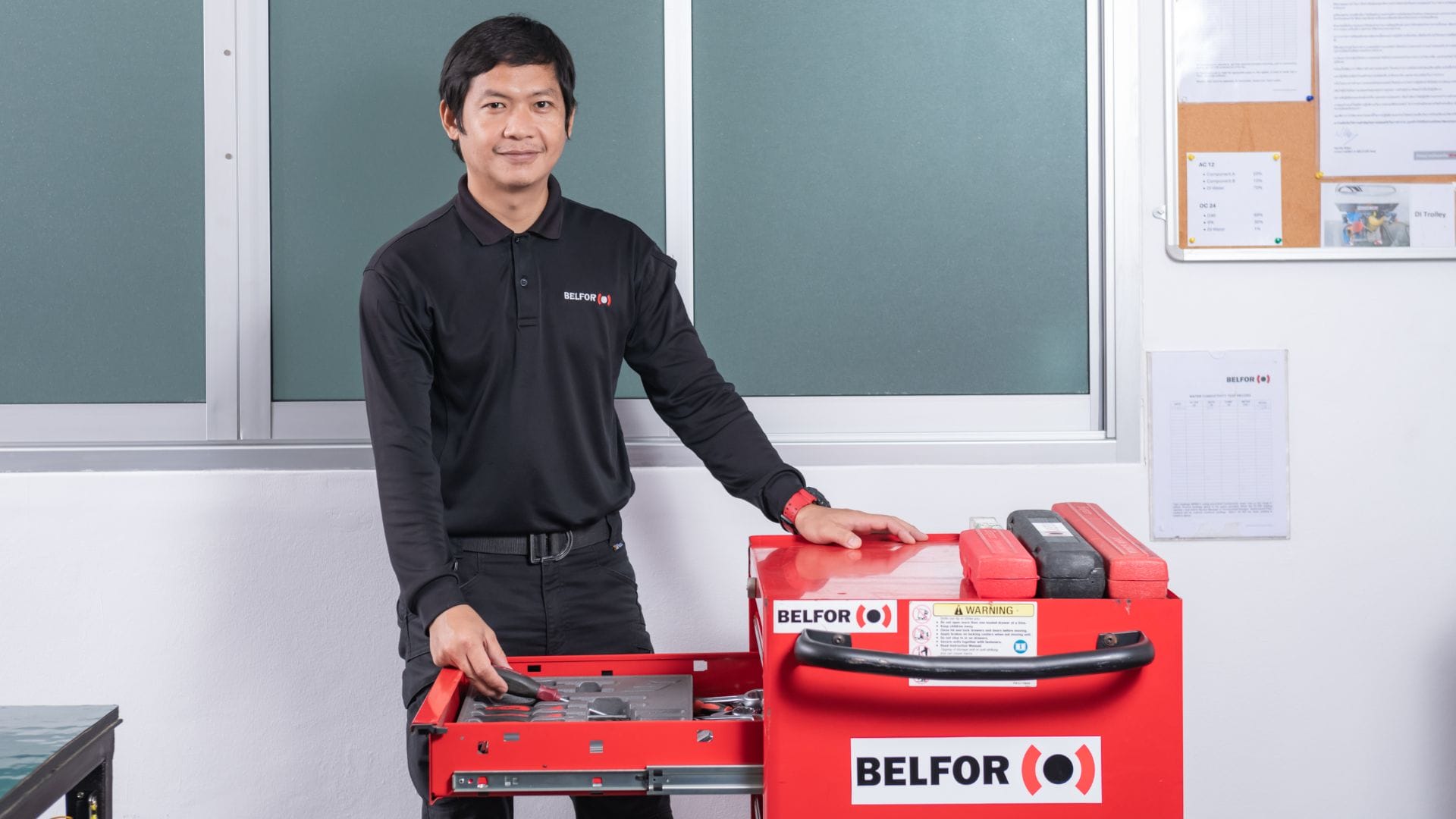 belfor technician standing next to a bright red toolbox, highlighting its features in the workshop environment