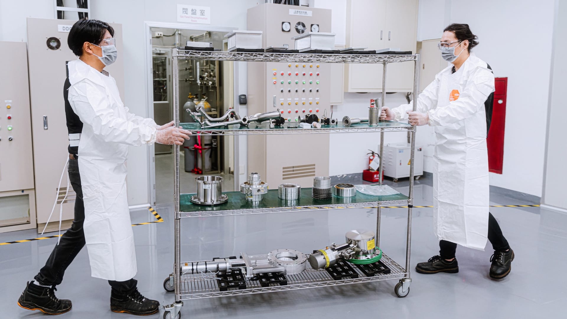 belfor-technicians-in-protective-gear-moving-a-metal-cart-filled-with-semiconductor-equipment-parts