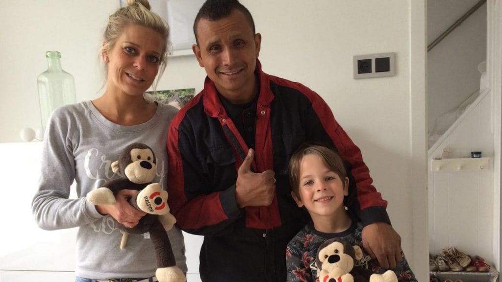 Family with one kid holding BELFOR NOAs and stading infront of a white wall